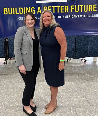 Maureen van Stone and another attendee smile as they stand next to each other at the  Americans with Disabilities Act 35th Anniversary Celebration.