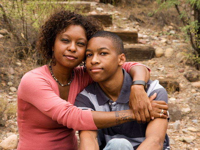 A mother hugs her teenage son.
