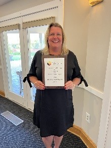 Maureen van Stone smiles while holding a plaque. 