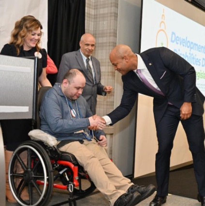 Maryland Governor Wes Moore shakes hands with People on the Go advocacy coordinator Mat Rice.