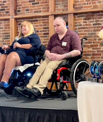Tracy Wright (left) and Mat Rice (right) sit on a stage together.