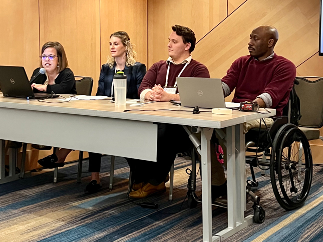 Chris Mason-Hale, Tyler Cochran, Tracy Waller and Leah Smith sit behind a long desk while giving a presentation.