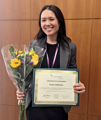 Kristine Nellenbach holds a bouquet of flowers and a Business Volunteers of Maryland certificate. 