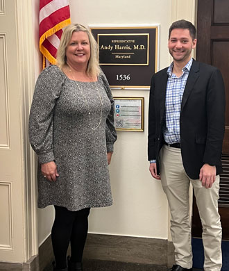 Maureen van Stone and a man stands in a hallway outside the office of Congressman Andy Harris.