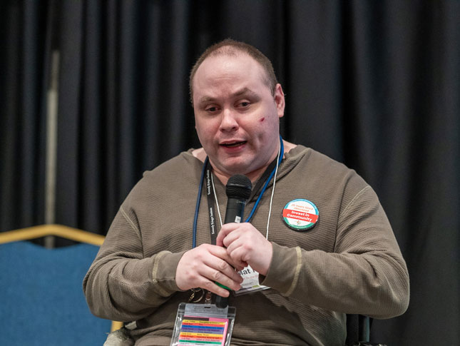 Mat Rice holds a microphone while giving a speech.