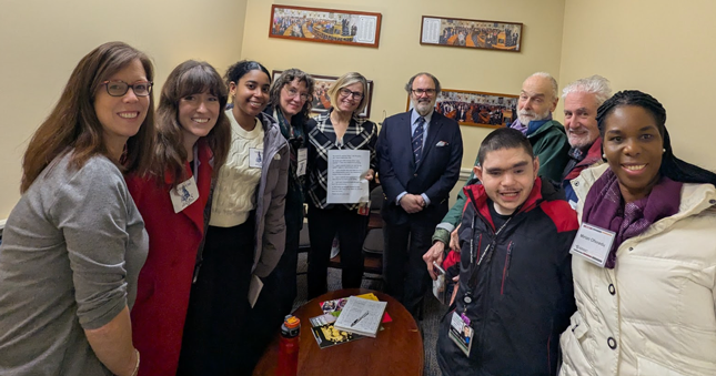 A group of people standing inside of a small conference room during Development Disabilities Day at the Legislature.