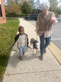 A woman and a little girl walk a dog as part of pet therapy session.