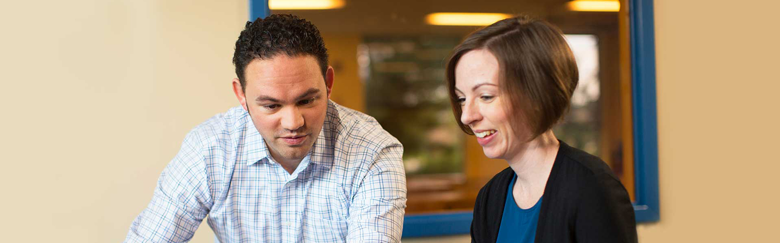 Two teachers review information on a laptop monitor.