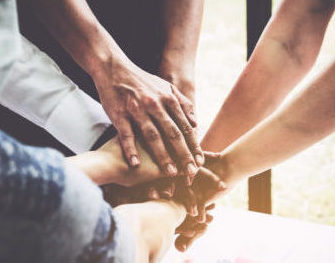 A group of people holding hands on top of one another