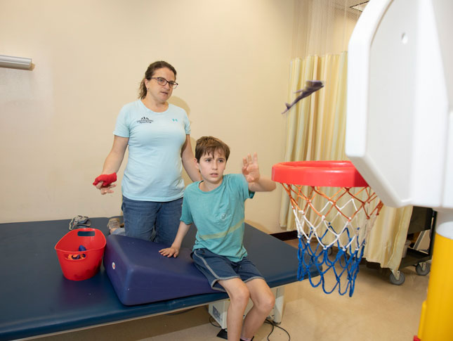 A young male patient and a female therapist perform rehabilitation at Kennedy Krieger.