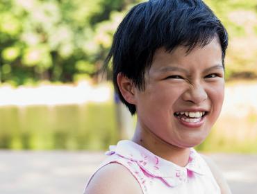 A child smiling brightly outside.