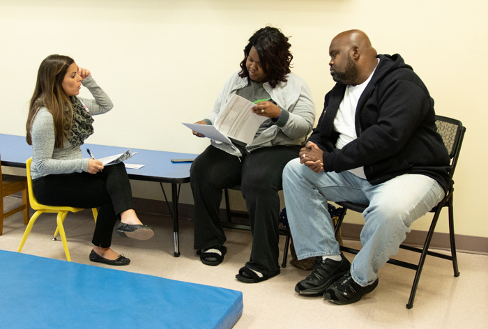 A mother and father look at documents and talk to a service coordinator.