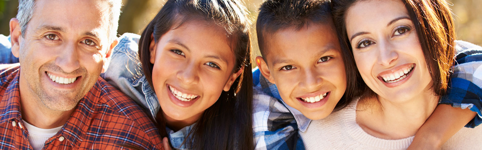 A father, daughter, son and mother smile in an outdoor portrait.