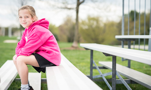 Morgan sitting outside on bleachers.