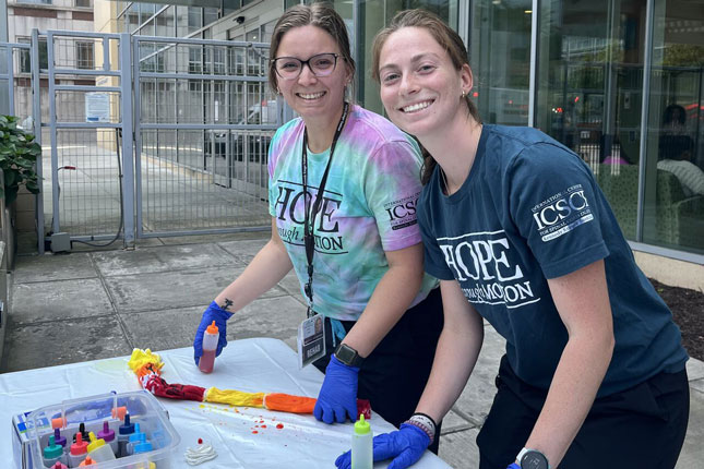 Two ICSCI staff members paint t-shirts as part of a 20th anniversary event.