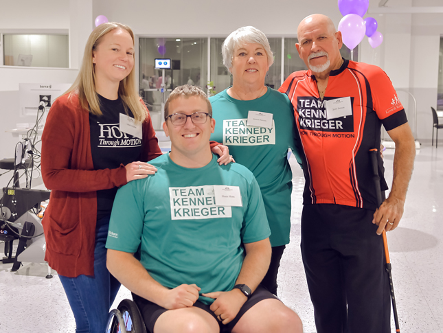 Two women and two men at the White Marsh location grand opening. Three of them are wearing Team Kennedy Krieger shirts, while one woman is wearing a Hope Through Motion shirt.