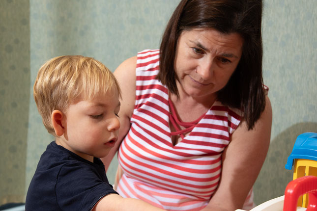 A physical therapist helps a young child during therapy.