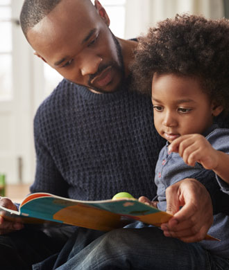 A father reads a book to his child. 