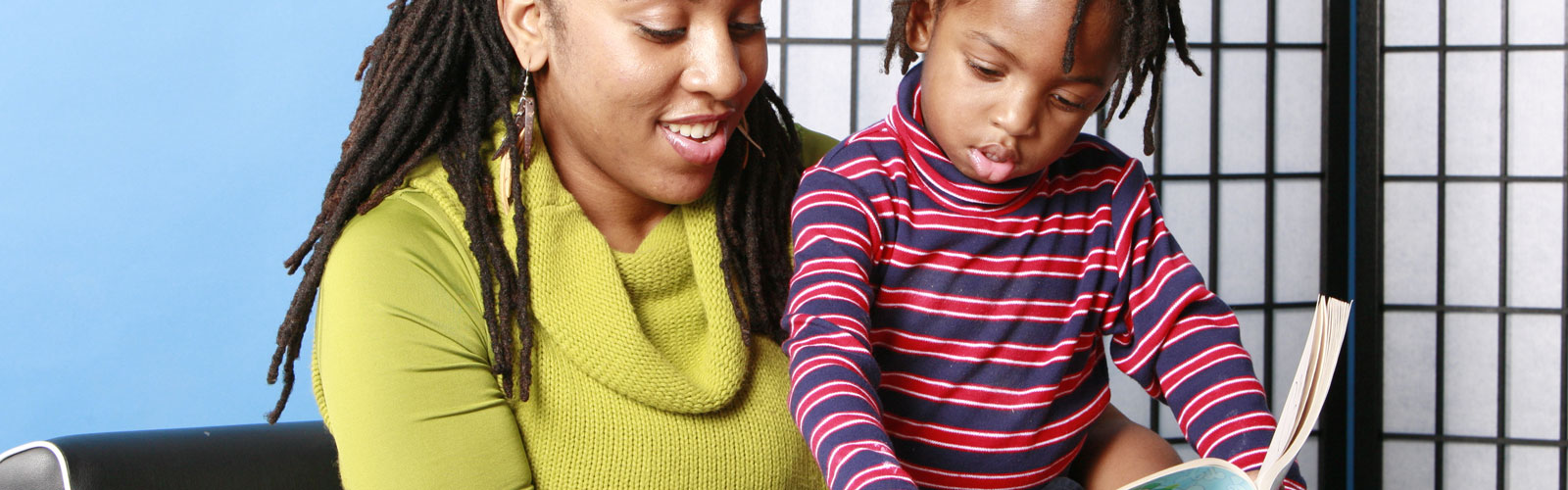 A mother holds her young son while reading to him.