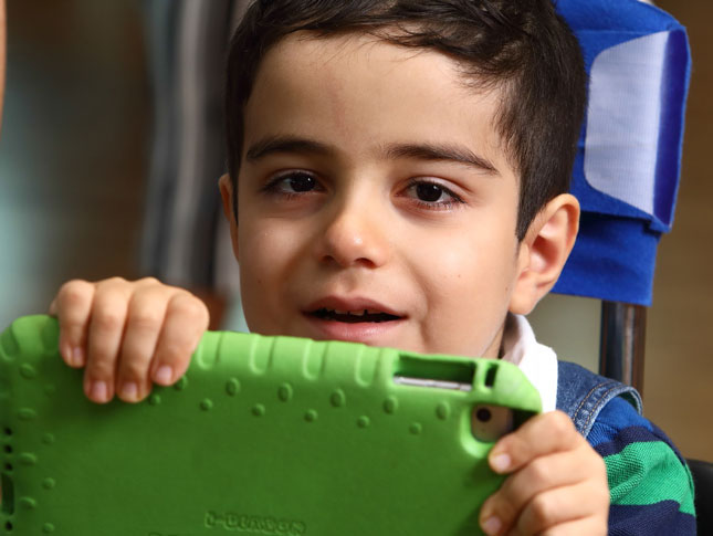 A young boy holds an iPad. 
