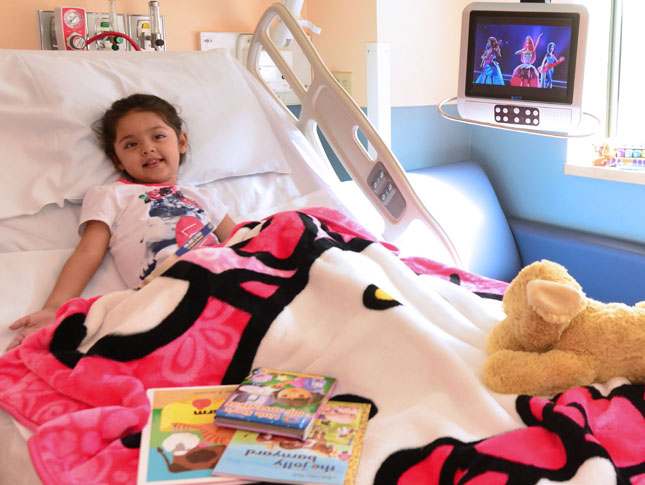 A young girl watches television in her inpatient room at Kennedy Krieger.