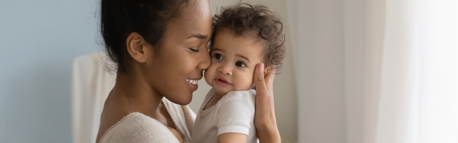 A mother holds her toddler and smiles.