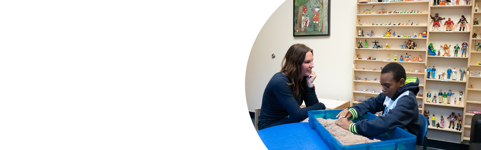 A Fairmount Campus teacher and student sit at a desk.