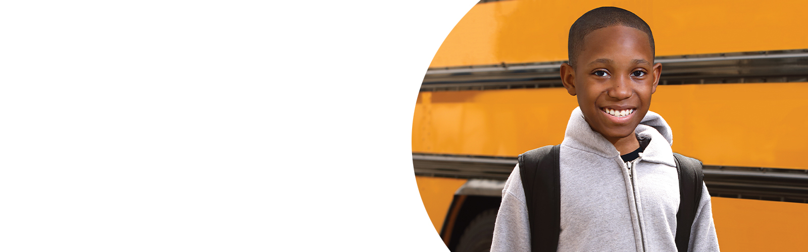 A Greenspring Campus High School student smiles while standing in front of a school bus.