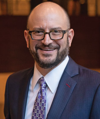 Portrait photo of a man wearing glasses and a suit and tie