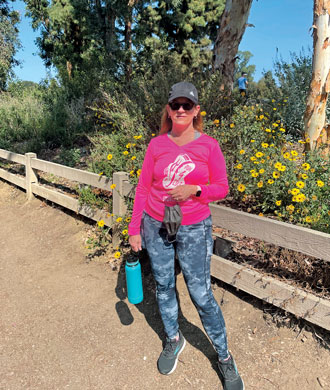 A woman in running gear, including a baseball hat, sunglasses and a shirt that says “Run 4 Cole”