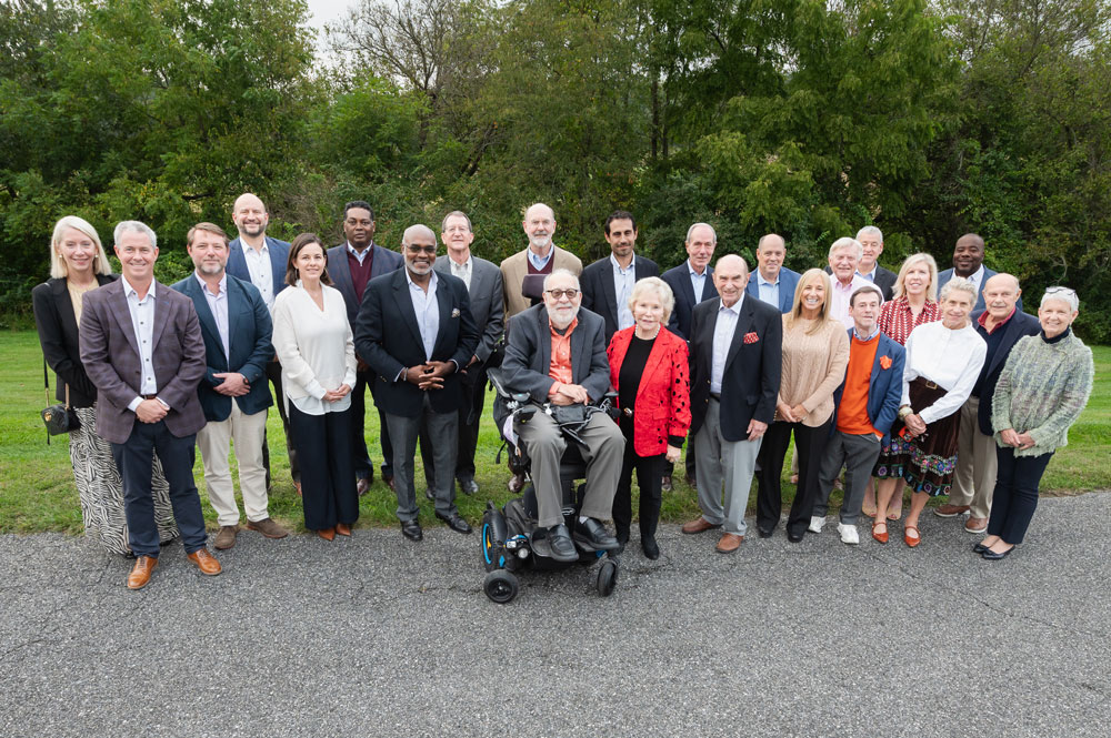 A group of Kennedy Krieger board members gather for an outdoor photo at a broad retreat. The board members shown are wearing professional attire. 