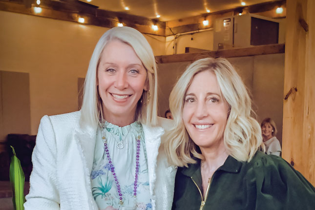 Photo of two smiling women, both with blond hair, at what appears to be a dressy event.