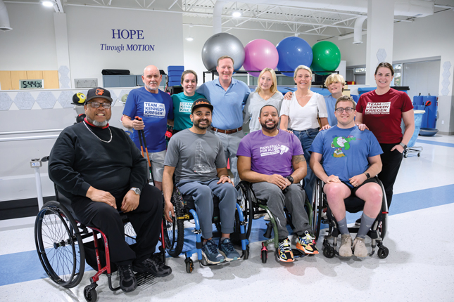 Beth deVillers with a group of adaptive sports athletes and spinal cord injury rehab staff members in one of Kennedy Krieger's therapy gyms.