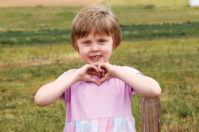 A little girl holds her in hands in the shape of a heart.