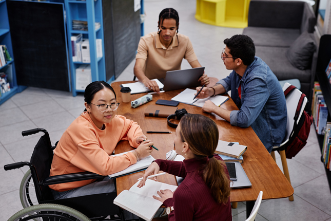 Four people sit around an accessible table.
