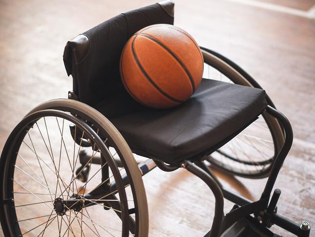 A photograph of a wheelchair with a basketball laying in the seat