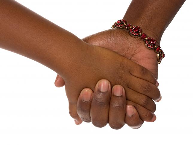 A photograph of a child's hand holding the hand of an adult