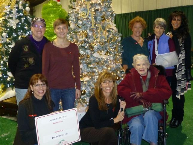 A photo of the Kemp family posing alongside their decorated tree at the Festival of Trees