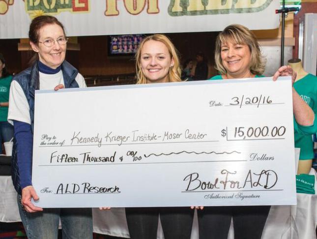 Taylor holds a check that shows the amount of money she has raised to support ALD research at Kennedy Krieger