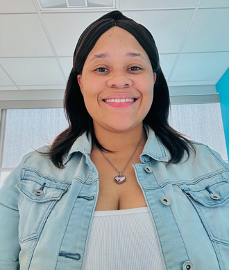 A young woman smiles and wears a headband and denim jacket.