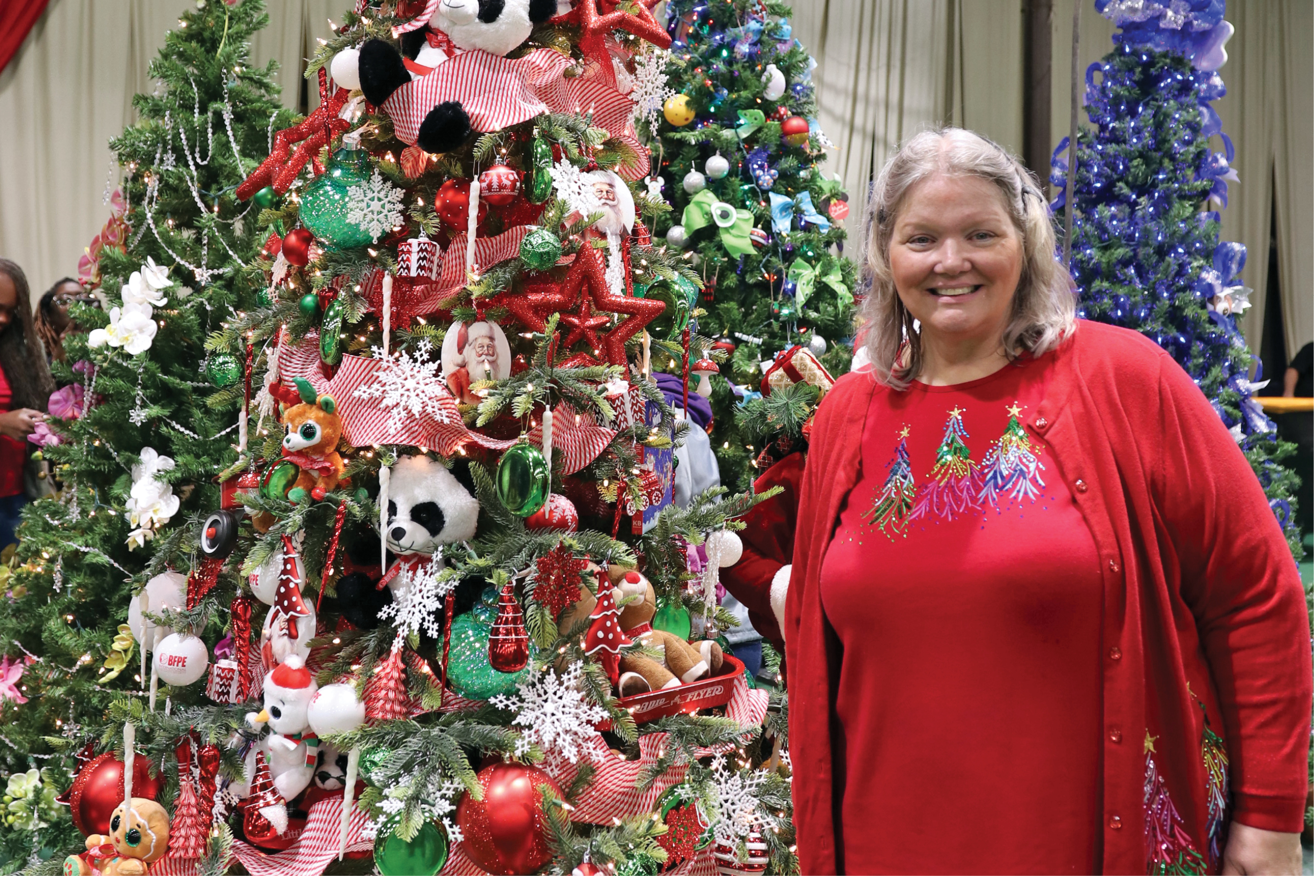 Sylvia Deck stands next to a decorated tree at Festival of Trees.