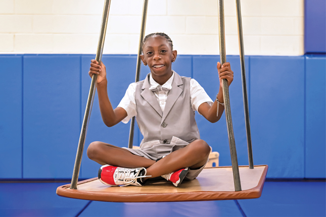 Chozin smiles while sitting on a swing.