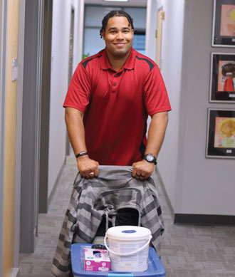 John Perry pushes a cart with supplies down a hallway.
