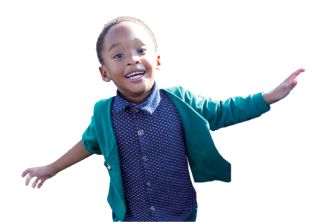 A young boy smiles at the camera while running, with his arms outstretched.