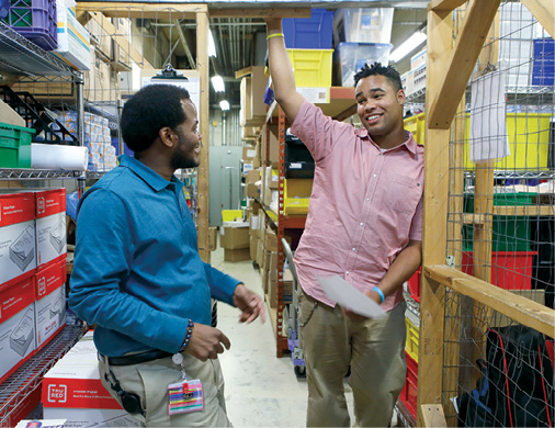 A photo of John Perry talking to Shawn Fallin, a fellow inventory technician who serves as John's mentor.