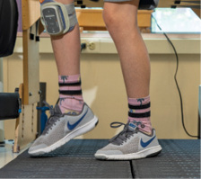 A photo of Brayden's legs as he uses a Bioness device while walking on a treadmill during physical therapy at Kennedy Krieger. The device delivers functional electrical stimulation to Brayden's right leg to improve his gait.