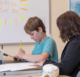 A photo of Brayden working with educational specialist Alecsandra Adler between therapy sessions at Kennedy Krieger's day hospital.