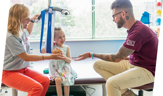 A photo of Ryleigh working with occupational therapist Frances Paradise and rehabilitation technician Shawn Reichenberg Jr.
