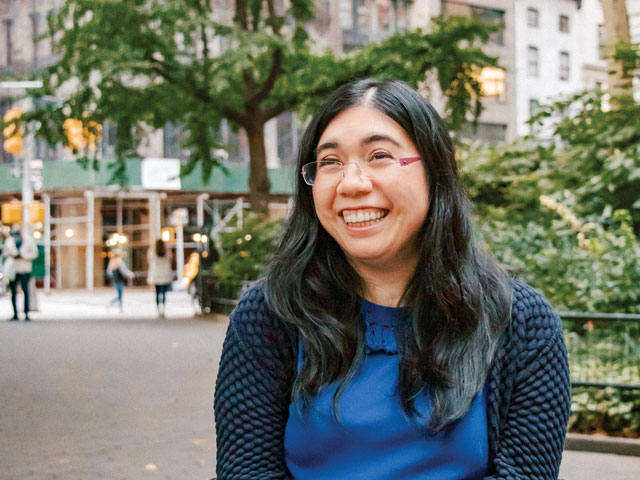 Valerie, smiling, sits in a wheelchair in an urban setting.