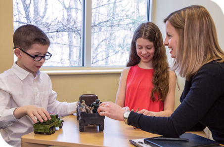 Dr. Lauren O’Donnell uses military action figures to talk about military life with Thomas and Reagan during a therapy session.